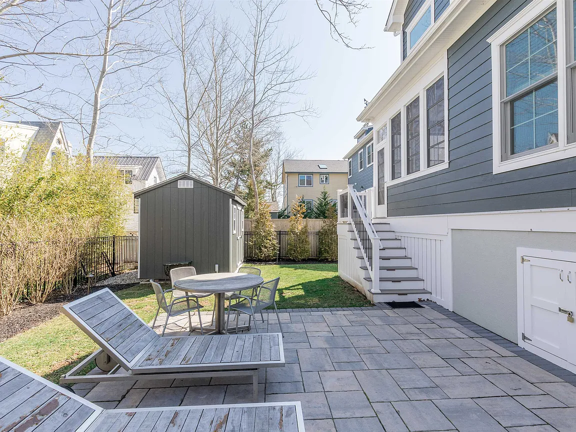 House backyard patio with lounge chairs and shed.