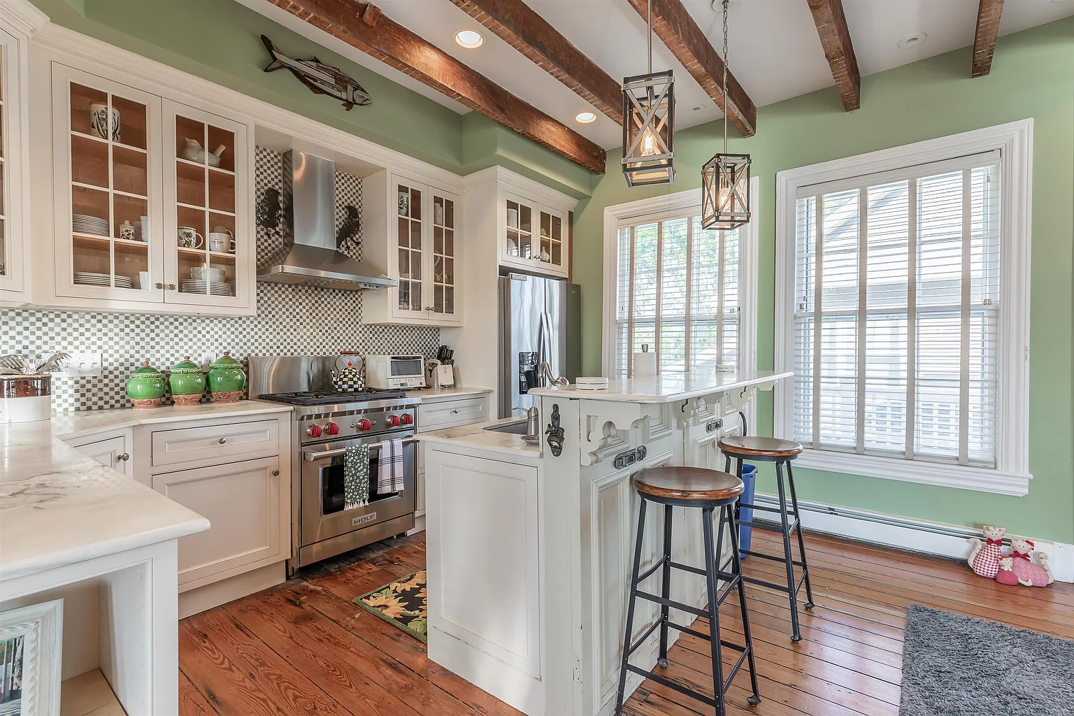 White kitchen with island and exposed beams.