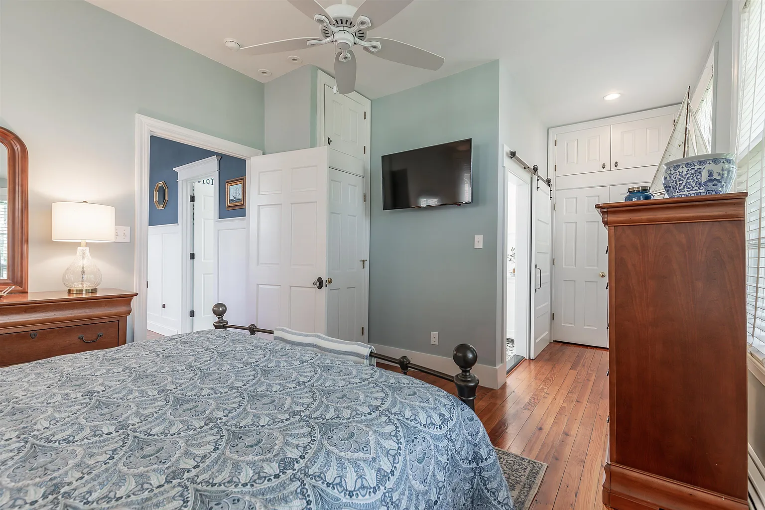 Blue bedroom with TV and hardwood floors.
