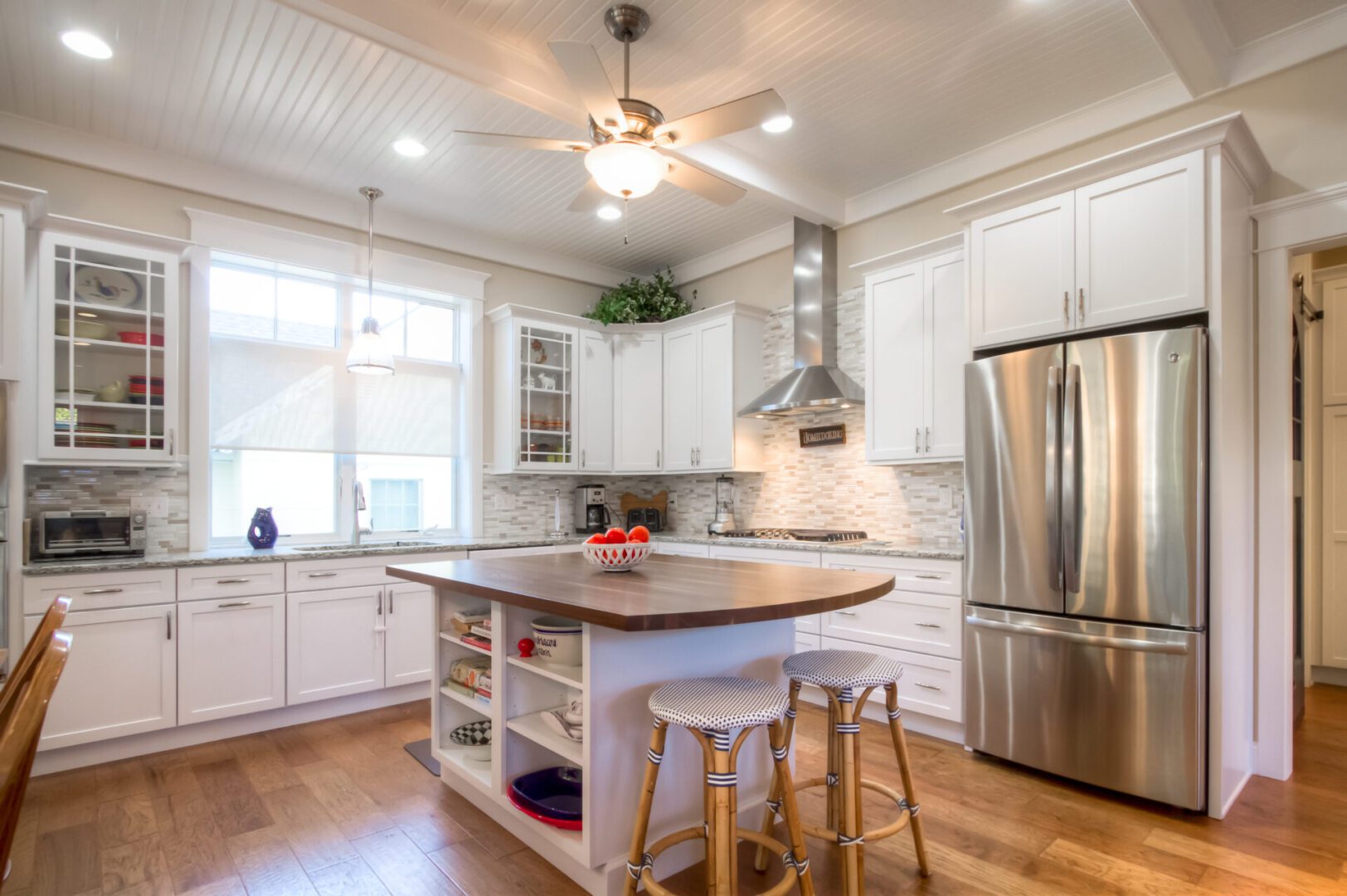 White kitchen with island and stainless steel fridge.