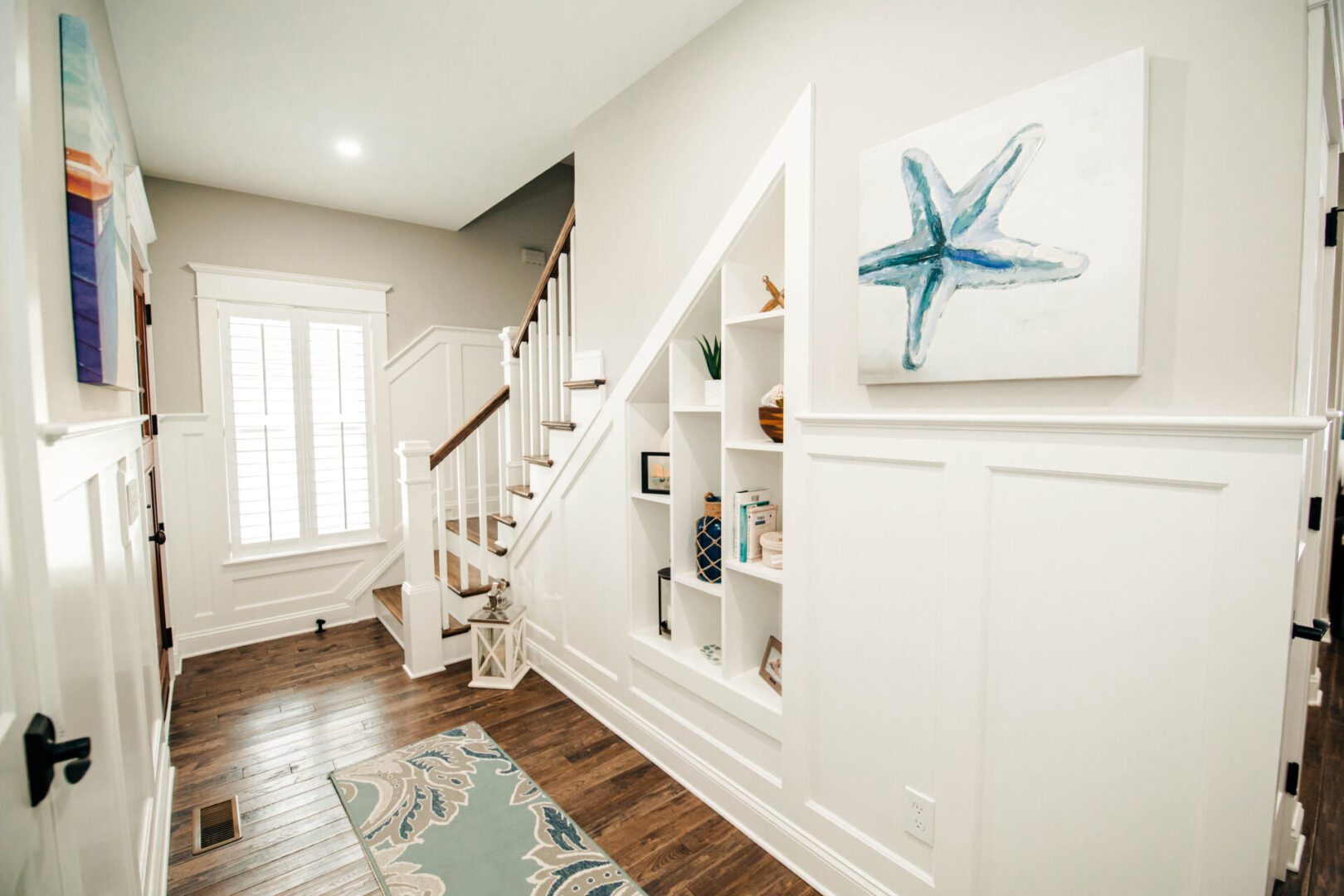 White entryway with built-in shelves and starfish art.