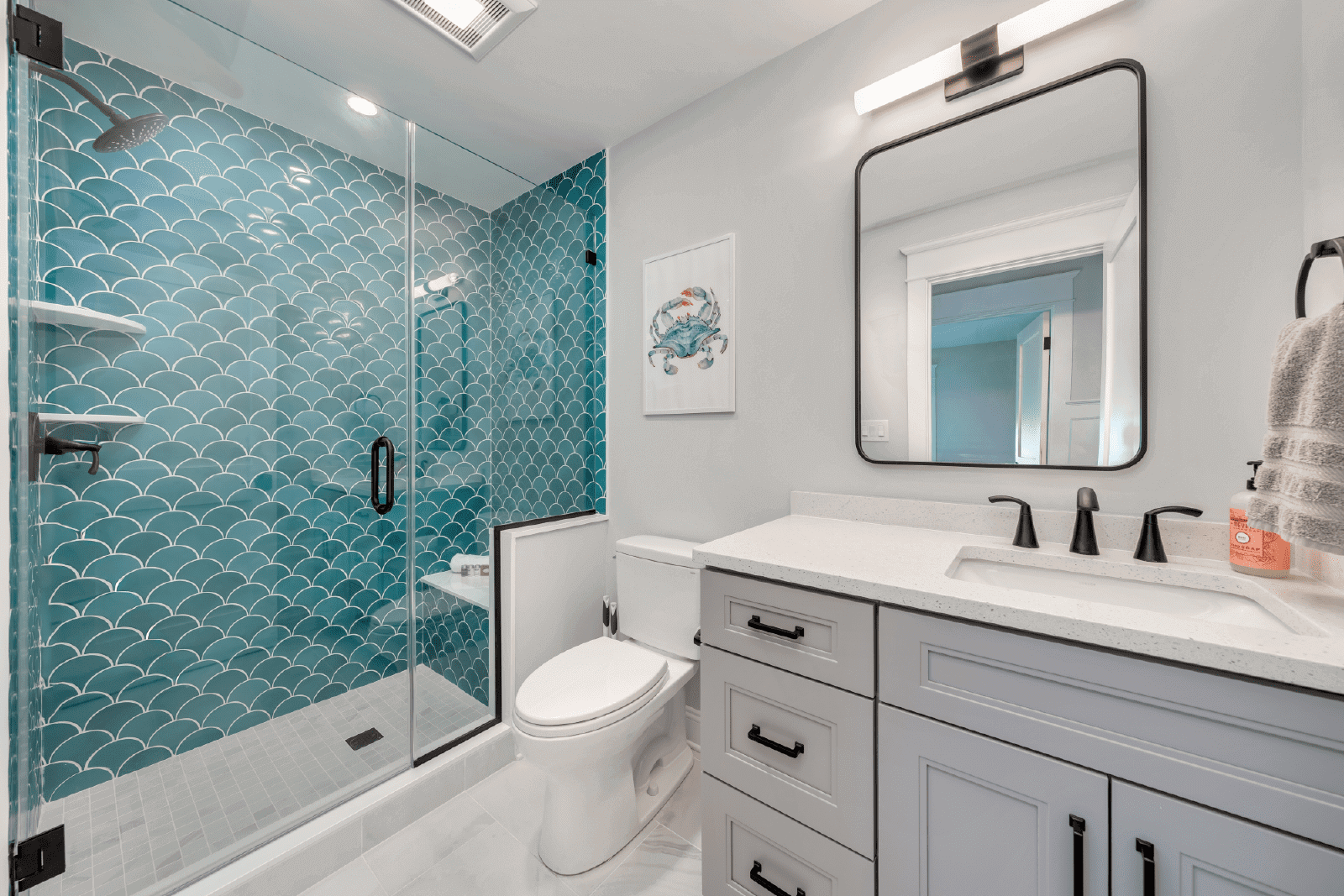 Teal scale-patterned shower and gray vanity.