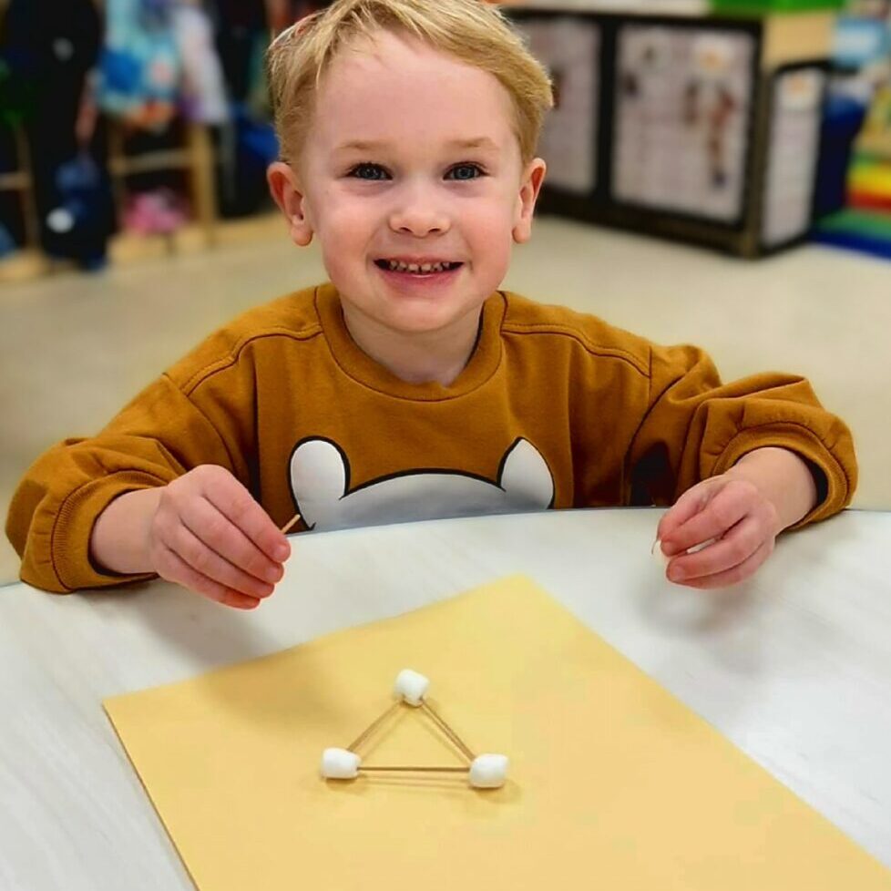 Smiling boy building a marshmallow triangle.